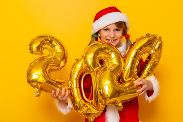 Girl wearing Santa costume holding balloons shaped as numbers 2020