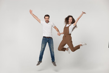 Excited young couple have fun in studio jumping