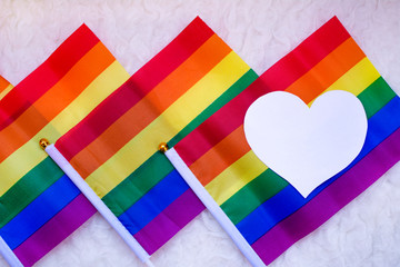 Colorful gay pride flags with a white heart on the left.