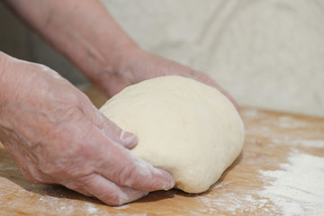 Hands of an adult woman cooking dough on  wooden background. Food concept