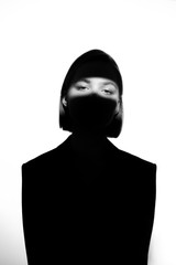 Fashionable beauty portrait. Black silhouette on white background. Girl with a spot of light on her face. 