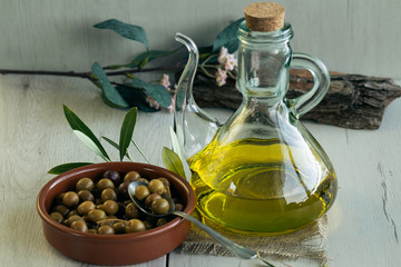  Olive oil and Arbequina olives on birch wood  glass bowl to pour olive oil. Also olive tree leaves