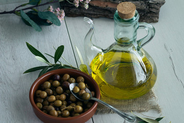  Olive oil and Arbequina olives on birch wood  glass bowl to pour olive oil. Also olive tree leaves