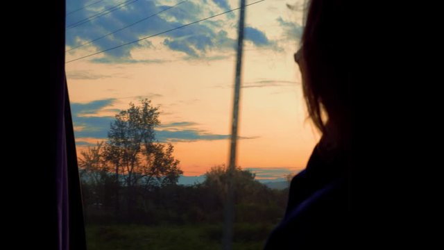 Girl watching sunrise over Caucasus mountains while traveling in marshrutka bus, Georgia