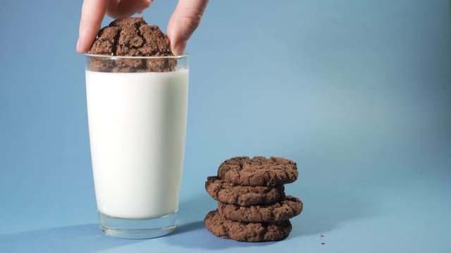 Female hand Dipping a chocolate chip cookie in milk. Slow Motion