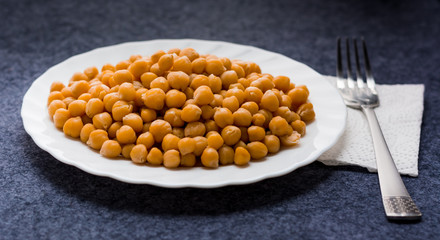 cooked chickpeas  on a white plate with a napkin and fork. Healthy food. Natural tasty.