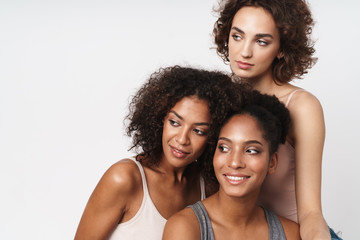 Portrait of three joyful multiracial women smiling and looking aside