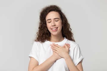 Thankful millennial girl with hands at chest feel gratitude