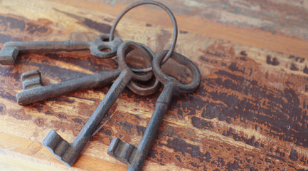 A bunch of old iron keys lies on an old wooden table