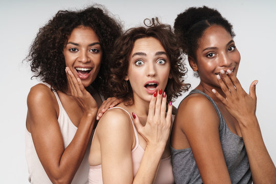 Portrait of three young multiethnic women looking at camera with surprise