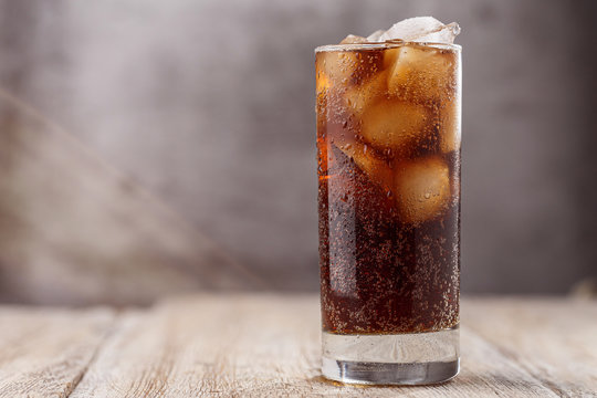 Cola with Ice Cubes. Glass of cola with ice cubes on wood table, soft drink. Copy Space.