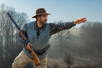 Hunting period, autumn season open. A hunter with a gun in his hands in hunting clothes in the...