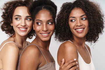 Portrait of three charming multiethnic women smiling and looking aside