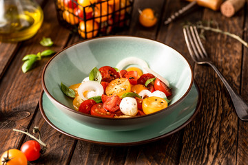 Yellow and red cherry tomatoes salad with fresh basil, mozzarella cheese and onion