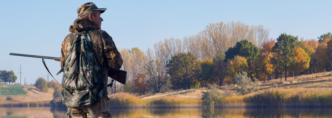 Hunting period, autumn season open. A hunter with a gun in his hands in hunting clothes in the...