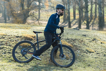 Naklejka premium Cyclist in pants and fleece jacket on a modern carbon hardtail bike with an air suspension fork. The guy on the top of the hill rides a bike.