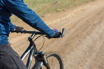 Cyclist in pants and fleece jacket on a modern carbon hardtail bike with an air suspension fork rides off-road.