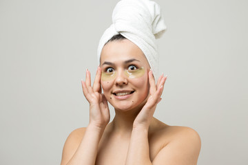 Young beautiful girl in a white towel on his head wears collagen gel patches under her eyes. Mask under eyes treatment face.