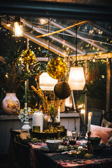 Decorated greenhouse in trendy christmas setting with dinner table, candles and christmas lights.