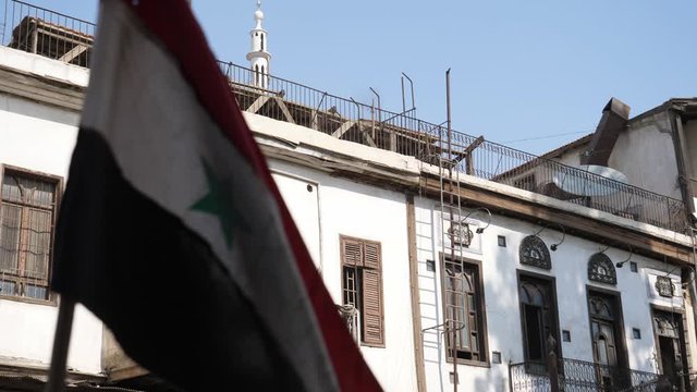 Syrian flag detail ruffled beautifully waving close-up shot, buildings in the background.