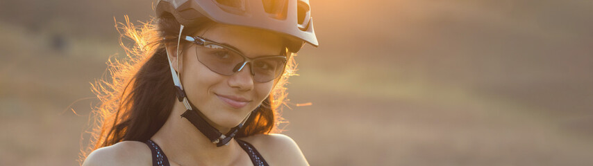 Girl on a mountain bike on offroad, beautiful portrait of a cyclist at sunset, Fitness girl rides a...