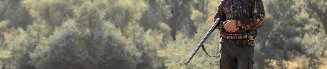 Hunter with a hat and a gun in search of prey in the steppe, Aims for prey. Panoramic image for...