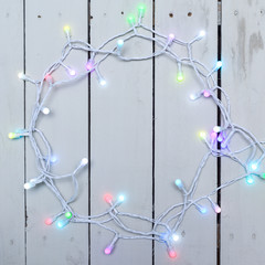 Christmas tree lights or fairy lights over festive white wooden board background with copy space