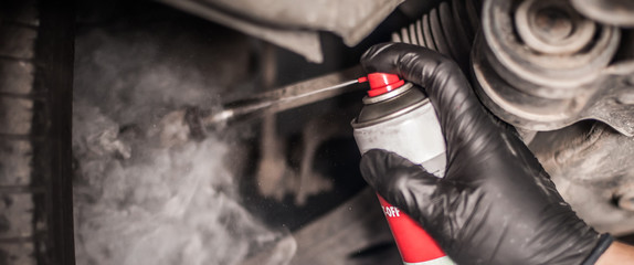 Fototapeta na wymiar Car master mechanic repairer lubricates screws with machine cleaner spray