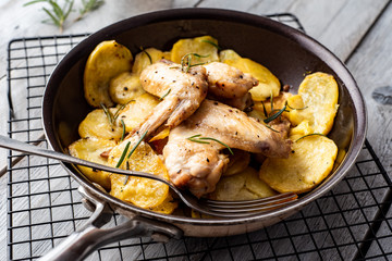 Baked chicken wings and potato chips with rosemary and garlic