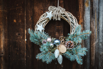 Christmas wreath on rustic wooden door background of blue tree.