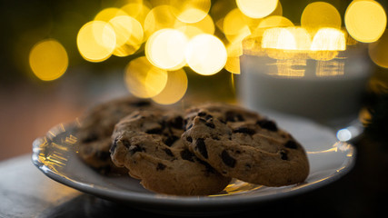 Christmas concept - cookies and milk left for Santa Claus, in front of christmas lights, bokeh
