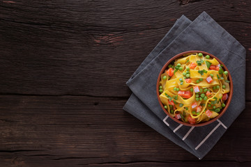Fettuccine pasta with salmon and green peas on a wooden table in a bowl. Top view.
