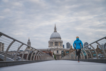 London marathon concept photo. Runner training on Millennium Footbridge, St Paul's Cathedral in background.