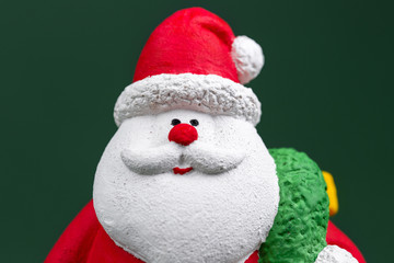 Cute gypsum colorful santa claus isolated over green background. New Year and Christmas concept.