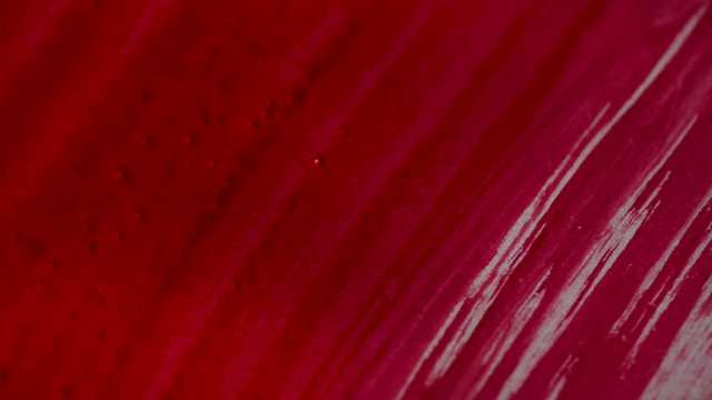 Drawing with a paintbrush on white paper with red watercolor close up. Texture and background