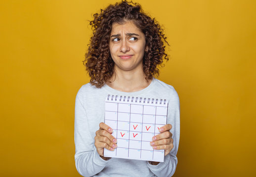 Portrait Of A Young Woman Holding A Calendar With Marked Days. Menstrual Period.