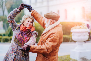 Happy old couple dancing at autumn park.