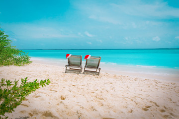 Christmas on beach -chair lounges with Santa hats at sea