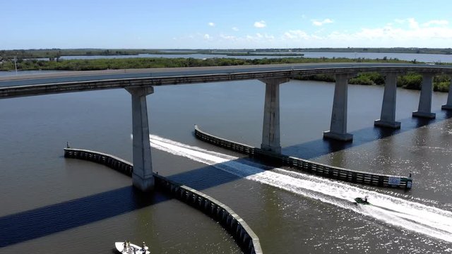 Aerial drone shot of a jetski going under a causeway on the Indian River Lagoon in Sebastian FL. Shot of a Beautiful summer day on the water in Florida. jet Ski goes under causeway.