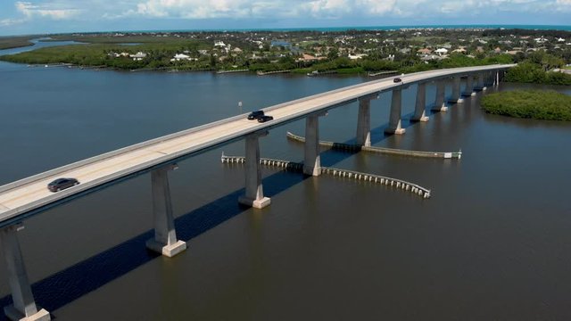 Aerial drone shot of a car going over causeway on the Indian River Lagoon in Sebastian FL. Shot of a Beautiful summer day on the water in Florida.