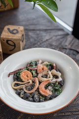 Black Conchiglie Pasta Shells with Seafood and Spinach. Modern Cafe Lunch.