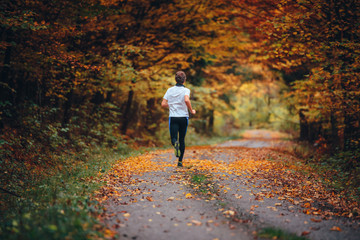 Runner trains in the picturesque autumn nature surrounded by colorful forest.