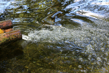 Water flowing from a spout into a clear stream