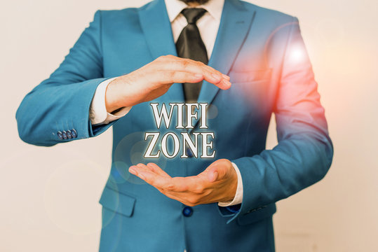 Conceptual hand writing showing Wifi Zone. Concept meaning provide wireless highspeed Internet and network connections Man in front of table. Mobile phone and notes on the table