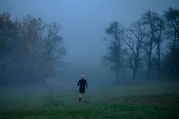 Runner in grey autumn misty morning, active life even in bad weather