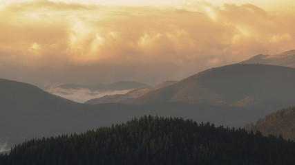Fototapeta premium Mountain range with visible silhouettes through the morning colorful fog.Tarcu Mountains in Romania.