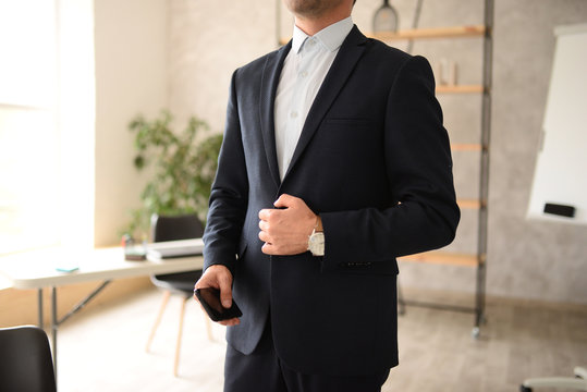 Unrecognizable man in suit holds mobile phone in the office