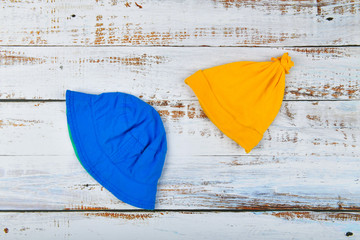 Baby hats on a wooden background. Blue Panama. yellow hat white wooden table. view from above.
