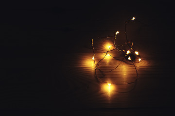 Golden christmas lights on a rustic wooden table. Copy space.