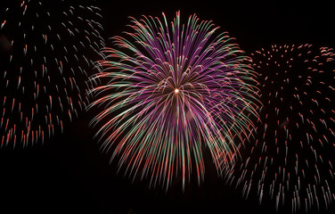 Cluster of colorful fireworks of various colors bursting against a black sky G